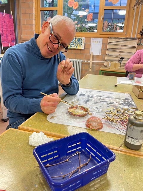 Roger Schubiger, Mitarbeiter Ateliers, bemalt mit Eifer die Äste für weitere Weihnachtsprodukte aus dem Atelier. Foto: zVg