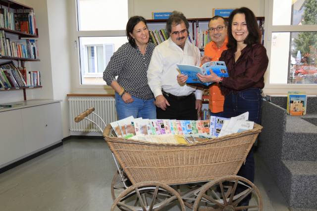 Das Redaktionsteam des «Zeiniger Schäsli» mit Janine Tschopp (von links), Thomas Freiermuth, Urs Kägi und Wendy Wohlfender. Vor ihnen steht ein «Schäsli» voller Dorfchroniken aus den vergangenen Jahren. Foto: Martin Wohlfender